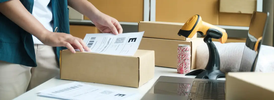 Person putting a shipping label on a brown cardboard package